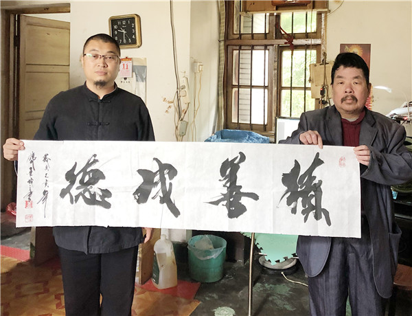1、2019年5月11日,永安市洪田马洪村中央红军标语博物馆研学旅行示范基地延学导师廖延斌(左)给管其乾送来书法“积善成德”(吴连盼 摄).jpg